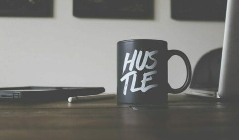 black and white Hustle-printed ceramic mug on table